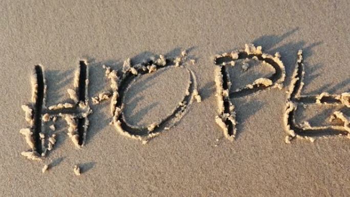 希望字写在沙滩上，并在日落时被海浪消灭