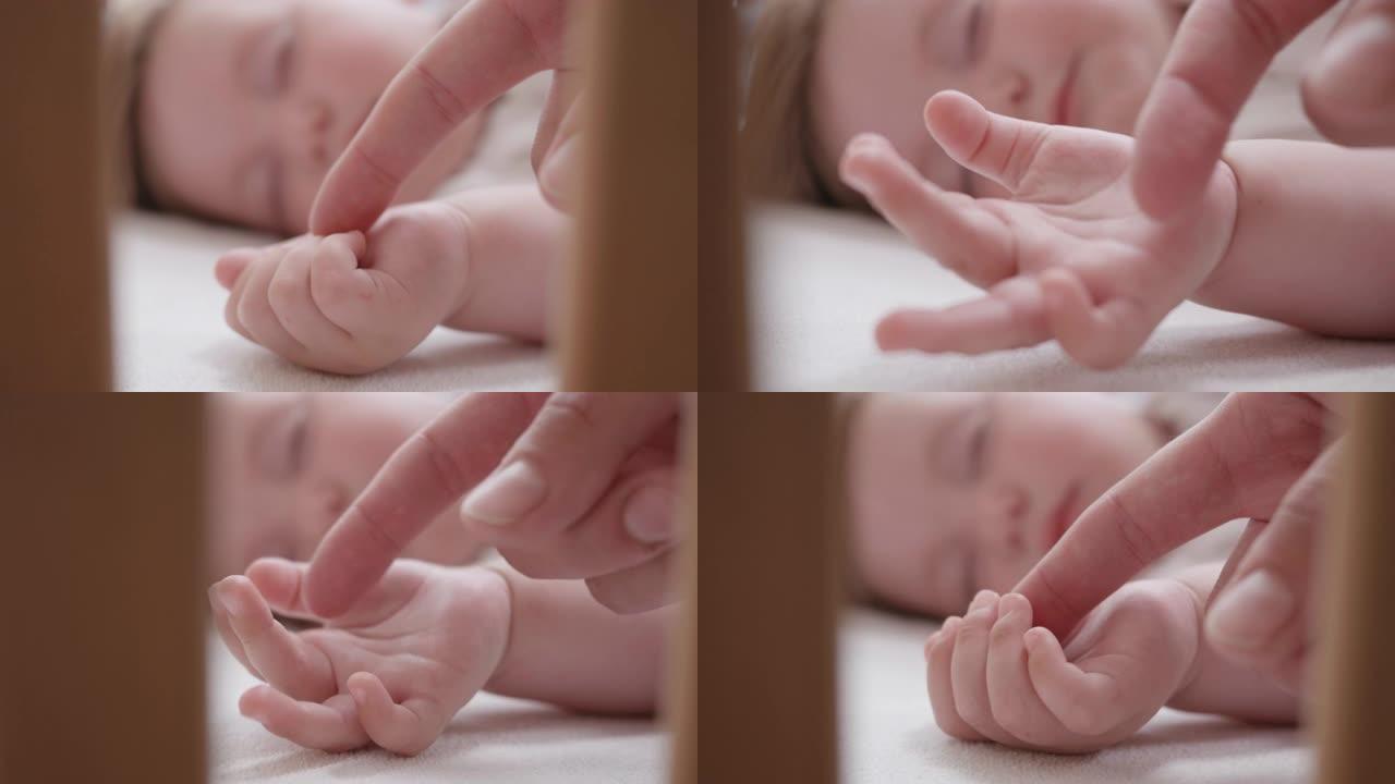 母亲爱抚熟睡的婴儿的手