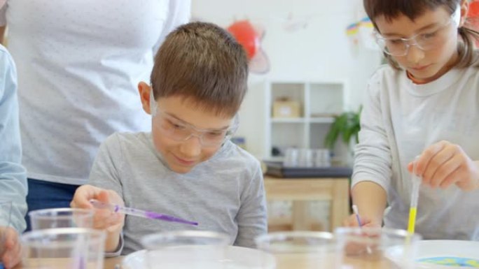 DS儿童使用滴管将颜色滴到盘子上进行科学实验