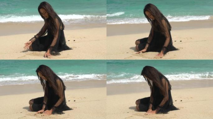 一个穿着黑色连衣裙的女孩轻轻地把手放在海边的沙滩上。