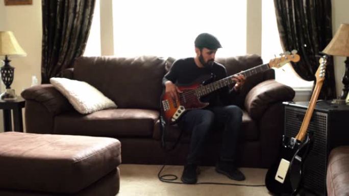 一个才华横溢的年轻人在客厅里练习低音吉他的视频剪辑