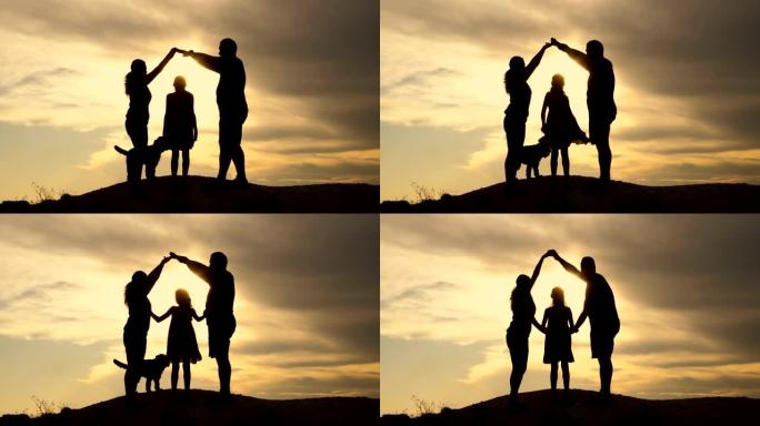 爸爸、妈妈、小女儿和狗在山顶上戏剧性的天空上。他们正在用手建造一个房屋标志。女孩跳舞。幸福家庭的概念