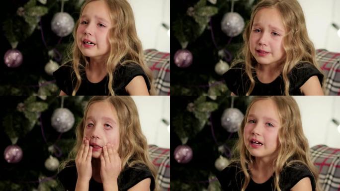 美丽，小女孩坐在圣诞树的背景中哭泣