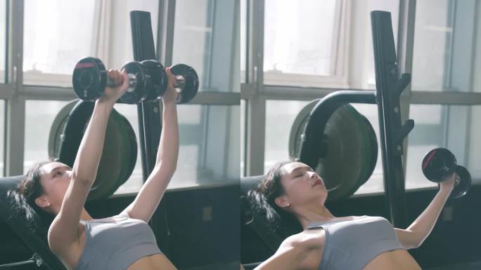 女性穿运动内衣在健身房使用哑铃锻炼