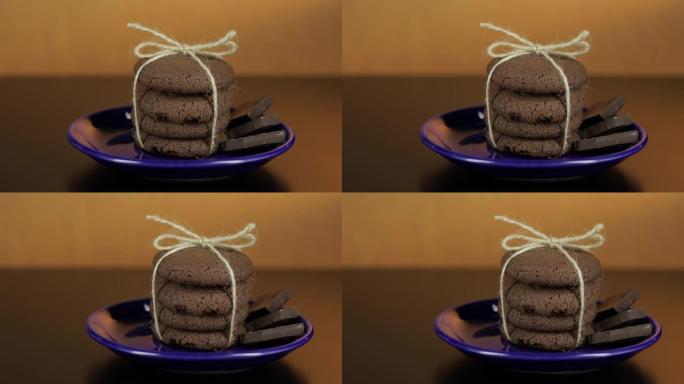深色表面蓝色盘子上看起来美味的巧克力饼干。温暖的背景