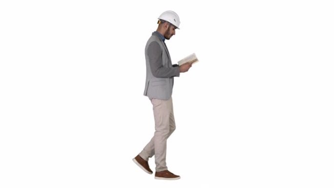 年轻的建筑师在白色背景上行走时阅读教科书或笔记本