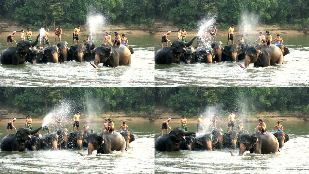 慢动作: 年轻人穿着传统的泰国服装，骑在河里美丽的大象上。大象从它的树干里吹水。