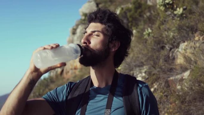 徒步旅行者站在山上对着天空喝水
