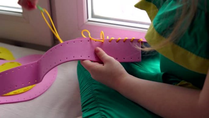 可爱的小女孩缝制一个粉红色的手提包。