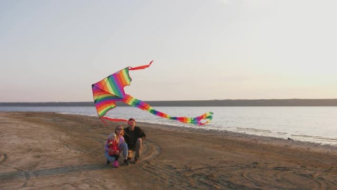 日落时海边放风筝的幸福家庭，慢动作