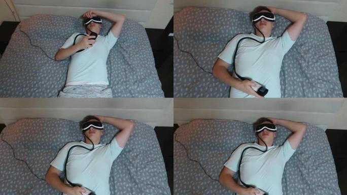年轻有魅力的男人使用眼睛按摩器装置，躺在床上，拿着遥控器，缓解乏力，放松，在笔记本电脑工作后休息