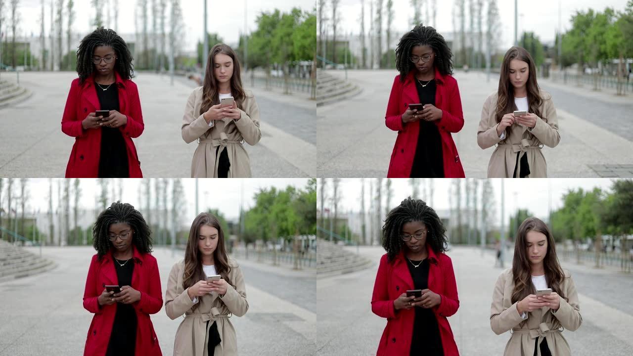 美国黑人和白人妇女走路，在电话上发短信