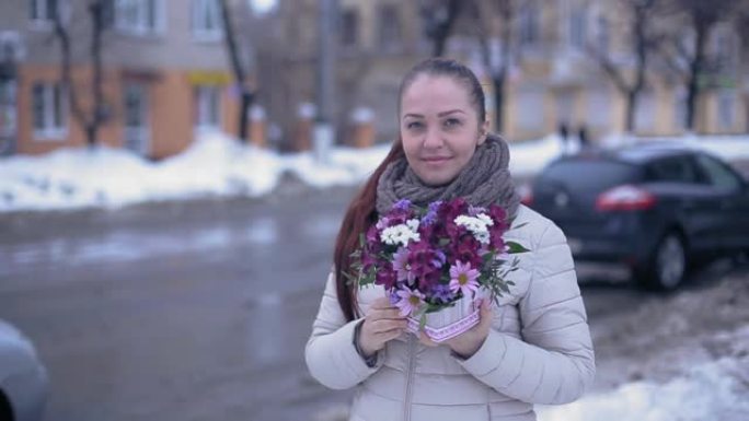 年轻的生活方式女人在早春的白雪皑皑的街道上鲜花