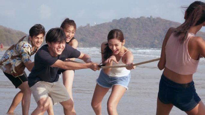 一群朋友在海滩上玩绳子时玩得很开心。