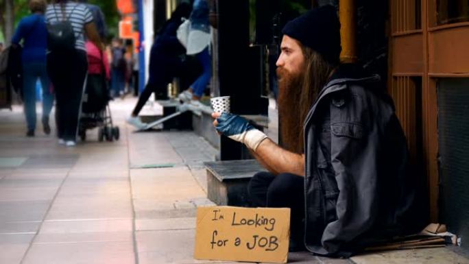 无家可归的人带着 “我在找工作” 的纸板，在拥挤的街道上乞讨