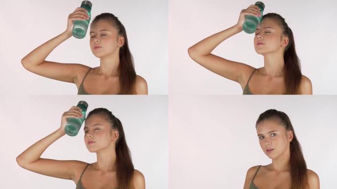 性感的女运动员拿着水瓶放在额头上，锻炼后休息