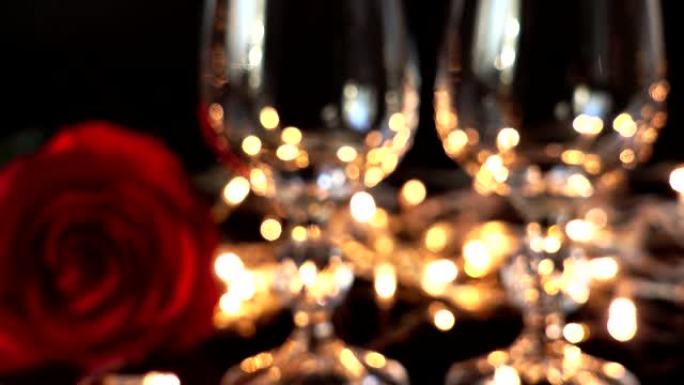 酒杯和玫瑰在明亮的花环的背景下。注意力不集中。