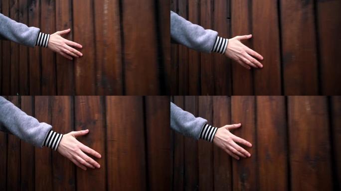 女性手触摸木墙。