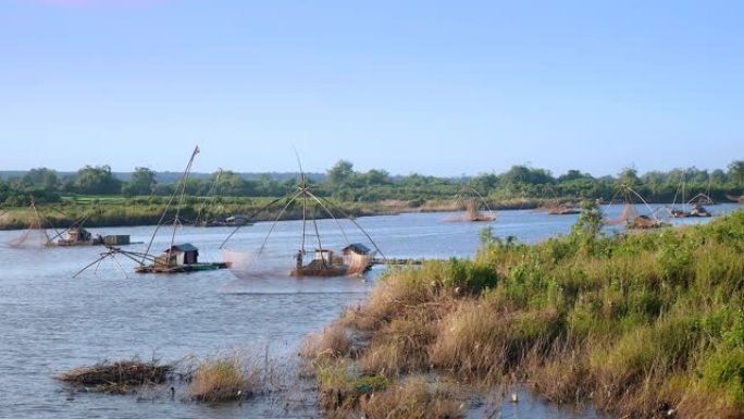 在河流上带有中国渔网的船屋和在前景中使用带有中国渔网的浸网的渔船