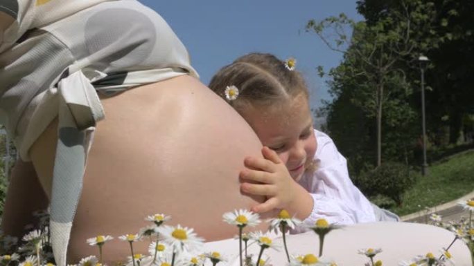 可爱的小女孩拥抱妈妈怀孕的肚子