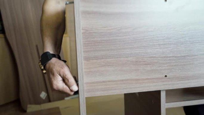 工人用螺丝刀和特殊螺钉组装并扭转木桌