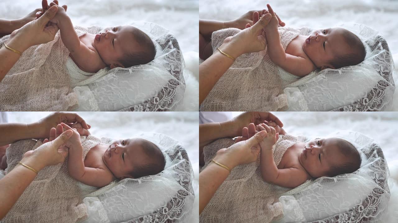 母亲牵手亚洲女性新生婴儿和阳光在早晨。可爱的小女孩三周大。医疗保健、爱情、关系概念
