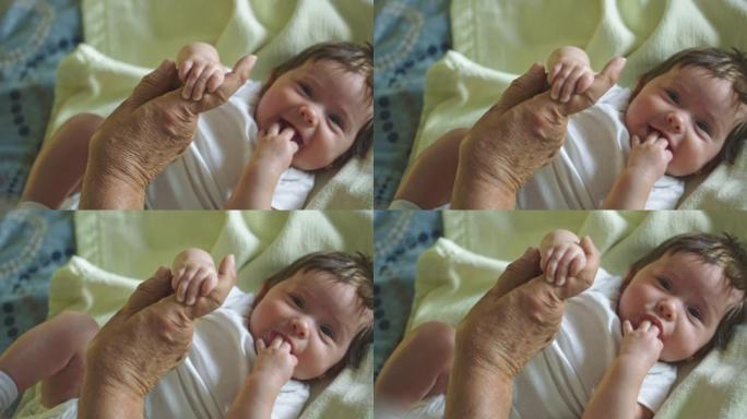 美丽的慢动作的婴儿微笑和握着祖父的手指