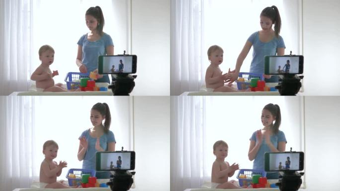 视频博客直播，可爱的男婴和妈妈一起用益智玩具玩，并在智能手机上为社交网络订阅者直播vlog拍摄新剧集