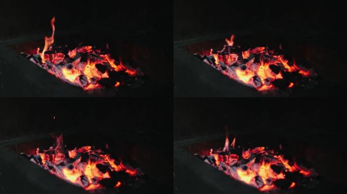 美丽的红色火从切片木材，深灰色黑色煤在金属火盆内。木头在火盆里燃烧着鲜黄色的火。火焰为烹饪烧烤做准备