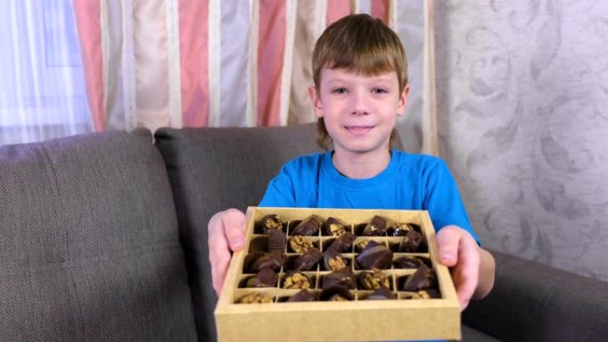 男孩在沙发上的盒子里展示巧克力。