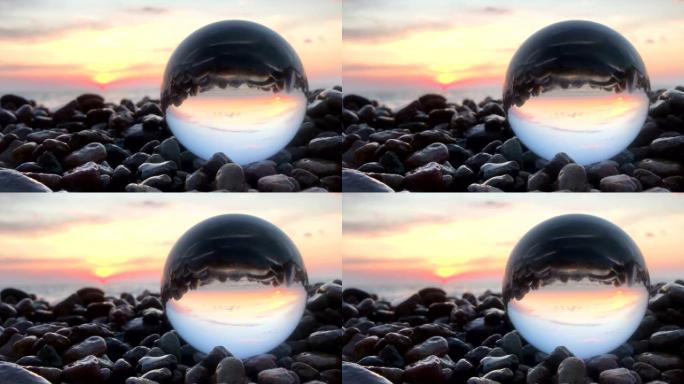 石头上水晶球内的美丽日落反射，水面上的太阳，海滩，风景