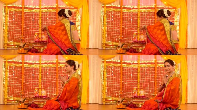 一名印度妇女面对着镜头，在家向印度教主的神像献花