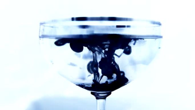 墨滴掉入装有水的玻璃烧杯中，然后慢慢沉入底部。