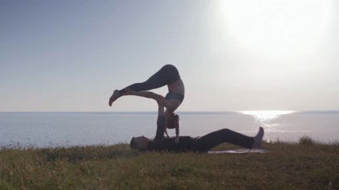 健康生活方式，瑜伽对在草地上做运动，享受大自然，海洋背景下的新鲜空气