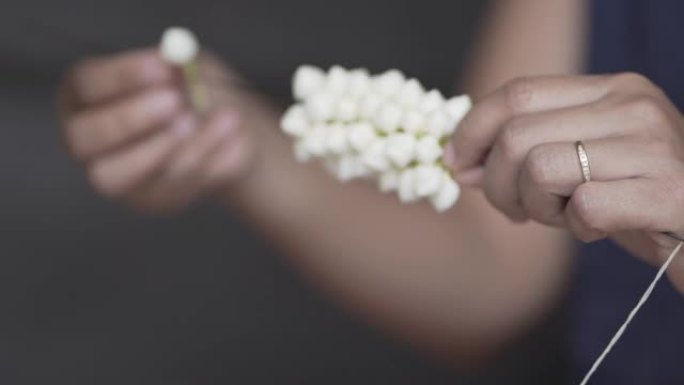 慢动作，年轻女子的手正在制作白色栀子花的美丽花环。