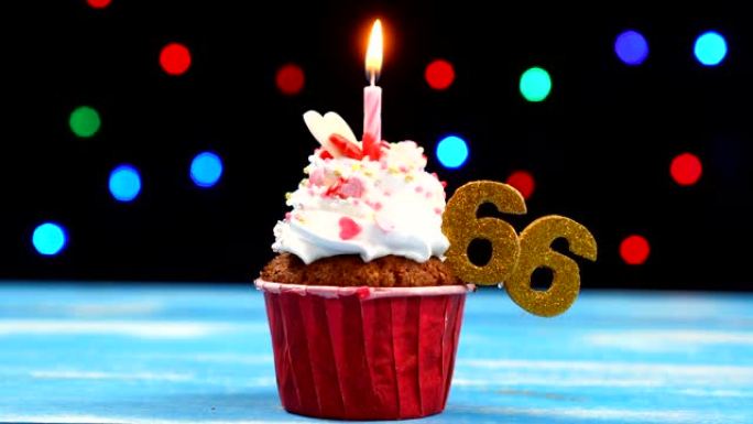 美味的生日蛋糕，带有燃烧的蜡烛和彩色模糊灯光背景上的66号