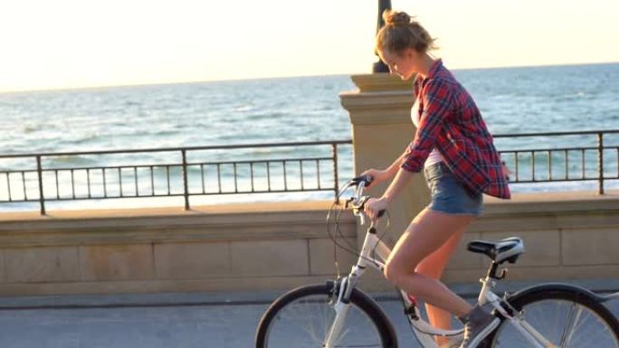 日落时分，年轻漂亮的女人在海滩上骑自行车