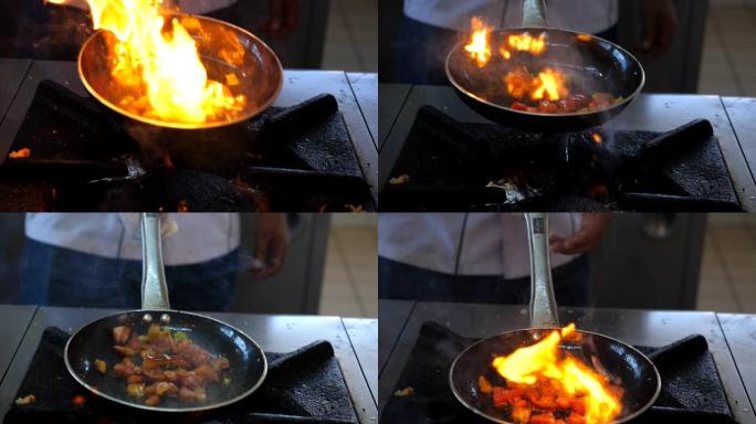 在酒店的现代厨房里，面目全非的厨师在平底锅上烹饪美味的flambe风格的菜肴。专业厨师在燃气灶上的燃