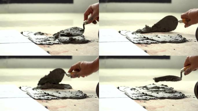 侧视图: 使用抹子将水泥作为瓷砖的瓷砖粘合剂放在地板上