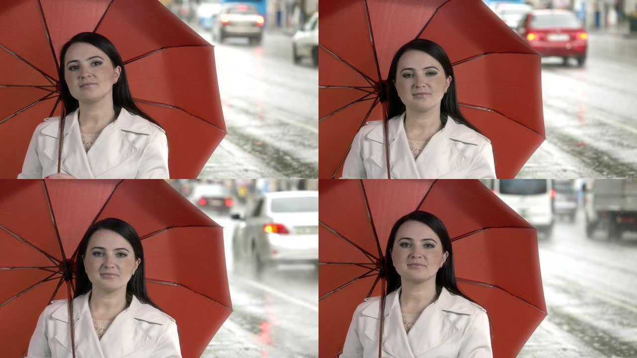 在城市街道的雨中拿着红色雨伞的女人。