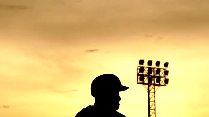剪影棒球运动员随著夕阳苦练