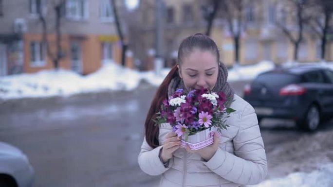 年轻的生活方式女人在早春的白雪皑皑的街道上鲜花