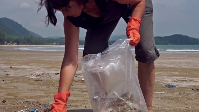 女性志愿者在环境污染海滩清理垃圾