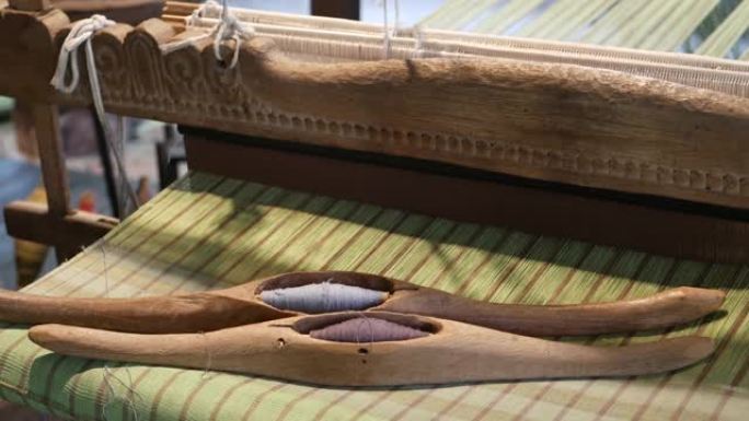 旧织机上的线。木制梭子，自然线放在编织的织物老化的织机上。