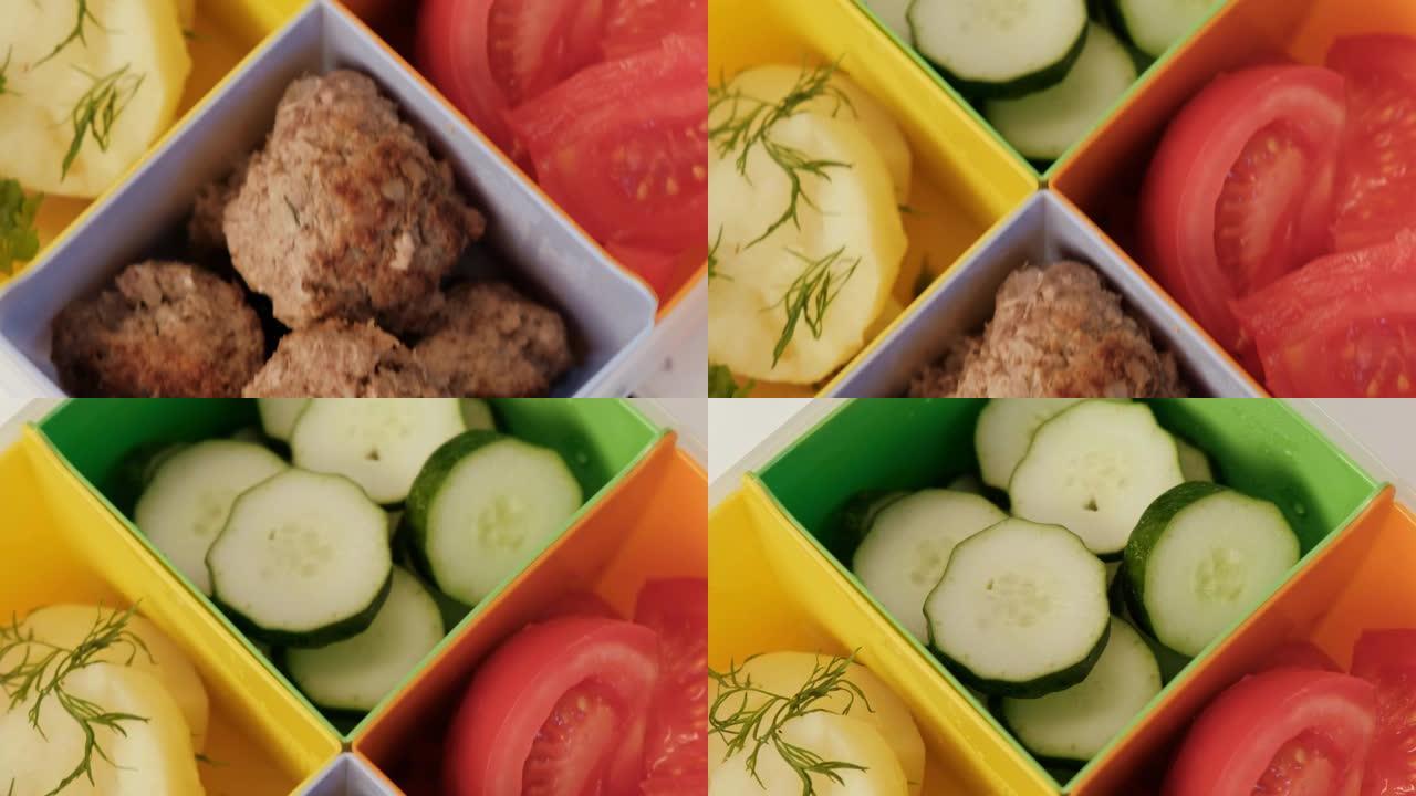 带牢房的午餐盒。蔬菜，黄瓜和西红柿，煮土豆和肉饼。