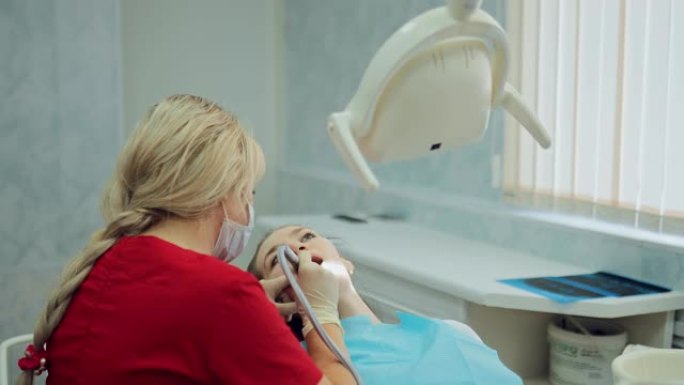 在现代牙科诊所治疗龋齿。病人张着嘴坐在医生的椅子上，女牙医钻了一颗牙。