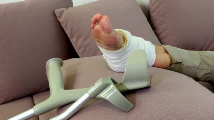女人受伤的腿和沙发上的拐杖特写