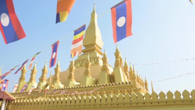 (选择性聚焦) 慢动作视频os老挝国旗在前景中挥舞，背景是美丽的Pha than Luang。Pha