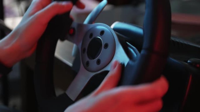 一个年轻游戏玩家的手在赛车模拟器的方向盘和按钮后面的特写镜头。年轻的玩家喜欢带轮子的赛车视频游戏。计