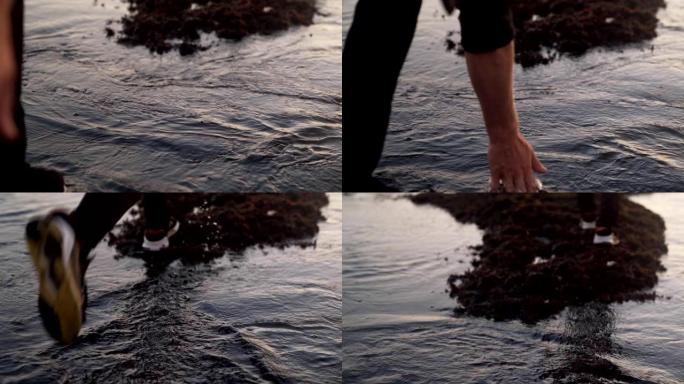 特写海水和穿着运动鞋的人的脚，迈出一步，用手触摸水，慢动作